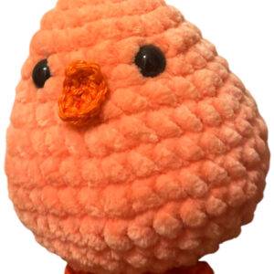 Ein kleiner, runder, orangefarbener Häkelvogel mit schwarzen Augen, einem orangefarbenen Schnabel und dazu passenden orangefarbenen Füßen, abgebildet auf weißem Hintergrund.